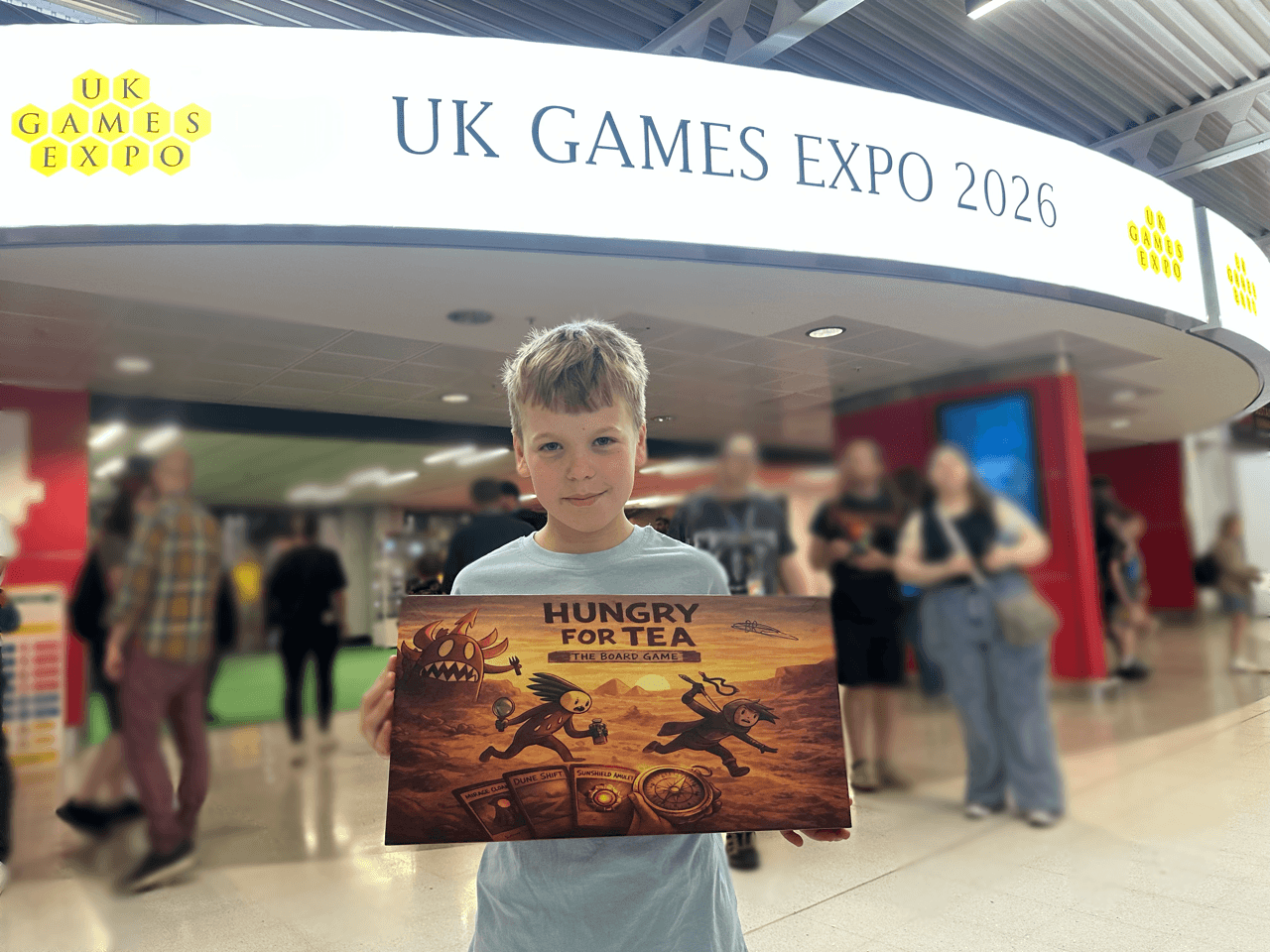 Benjamin holding Hungry for Tea outside the UK Games Expo 2026 entrance